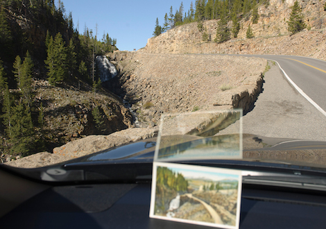 Nineteenth century postcard of Yellowstone placed on a car dashboard in the same modern day landscape.